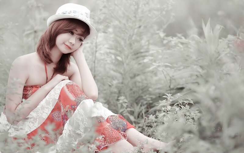 woman in hat sitting in field