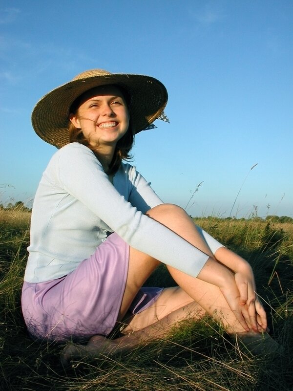 Woman in hat sitting in field