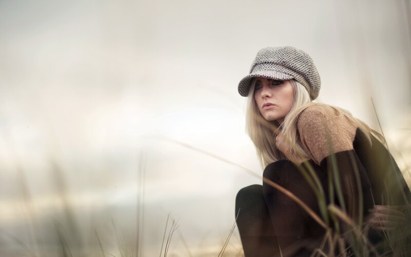 woman in hat sitting in grass