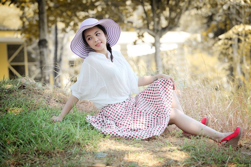 Woman in hat sitting on grass