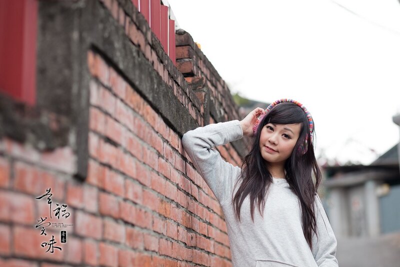 woman in headphones by brick wall