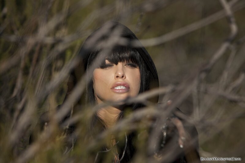 woman in hood behind branches