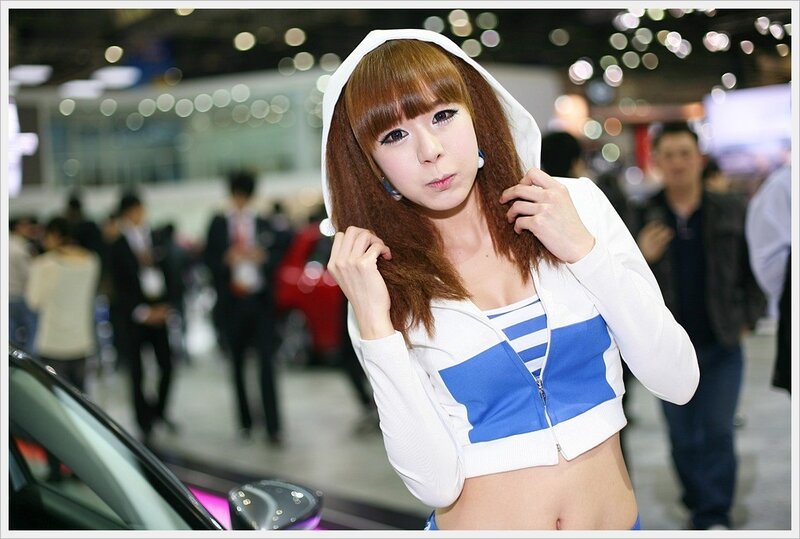Woman in hooded jacket at auto show
