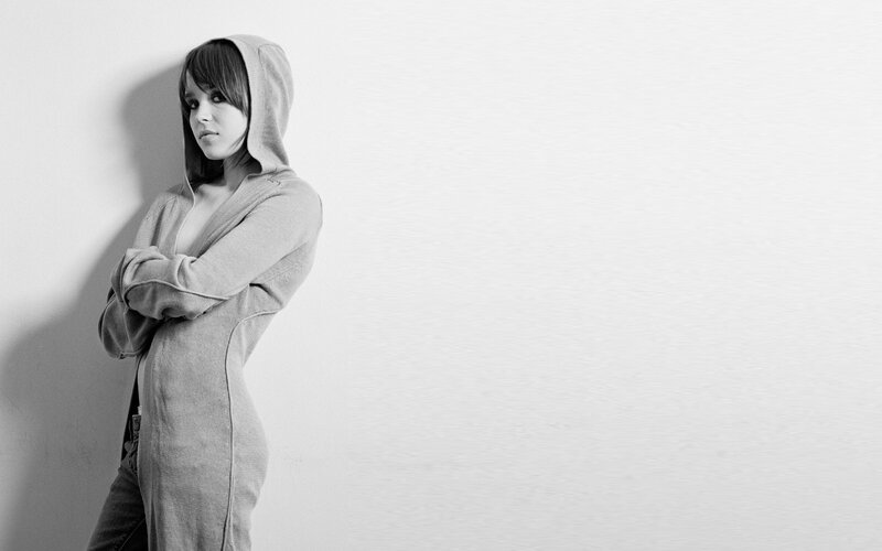 woman in hoodie leaning against wall