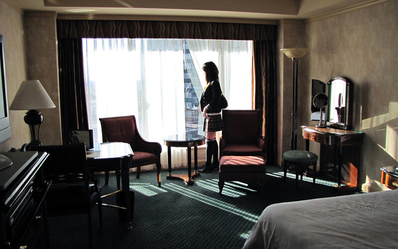 woman in hotel room looking out window