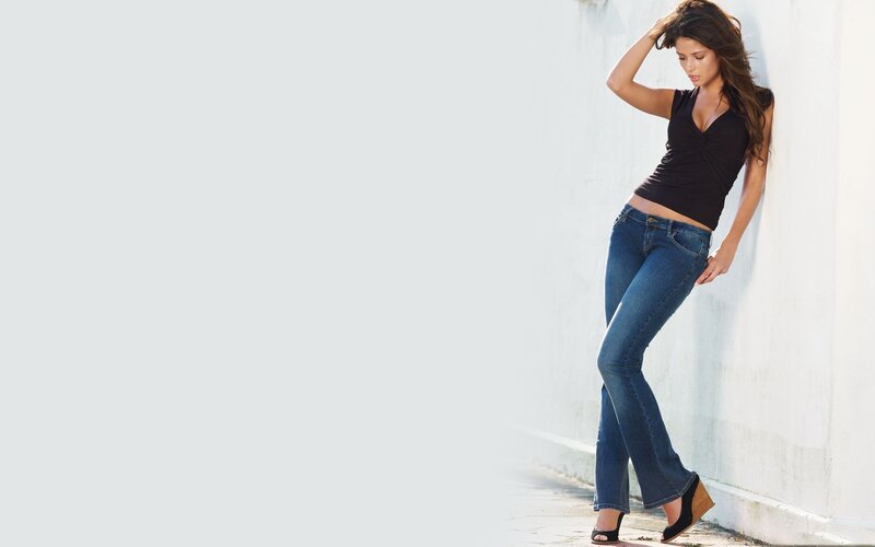 woman in jeans leaning on wall