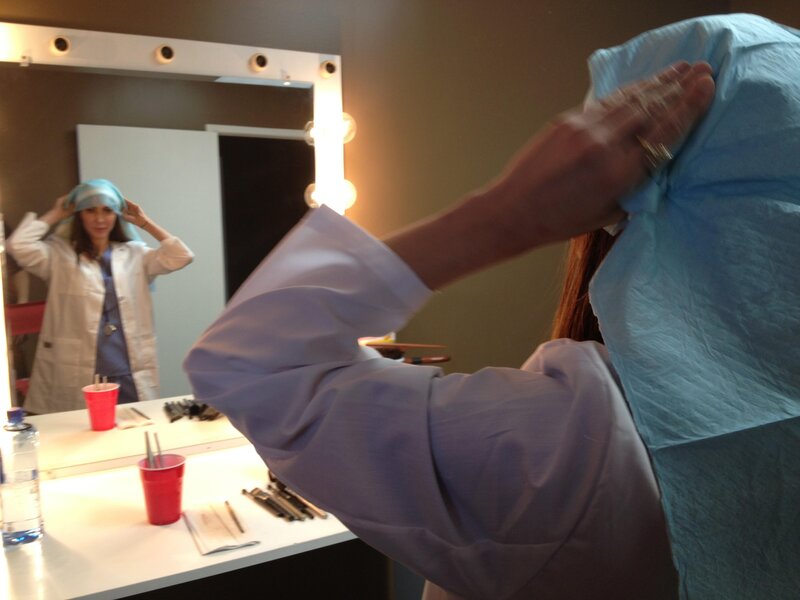 woman in lab coat adjusting head covering