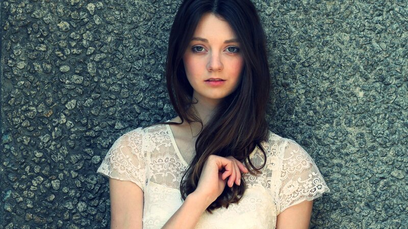 woman in lace dress against stone wall