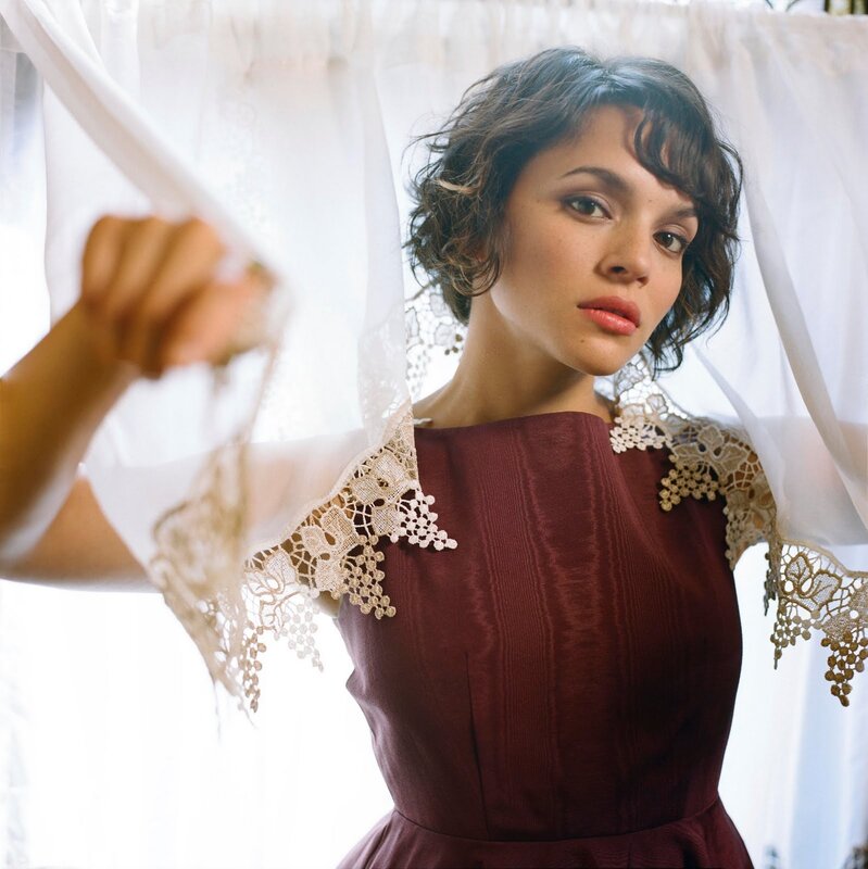 woman in lace dress behind curtain