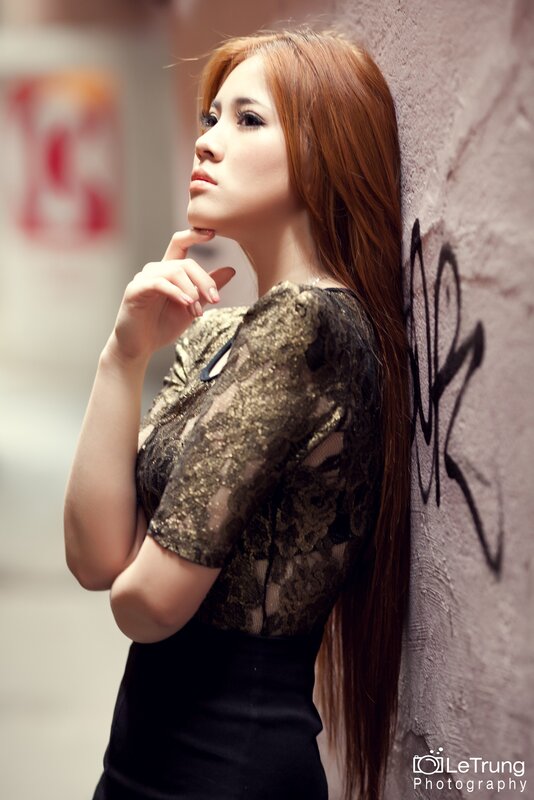 woman in lace top leaning on wall