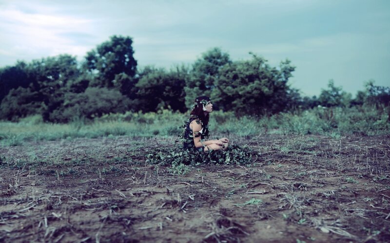 woman in leaf crown sitting in field