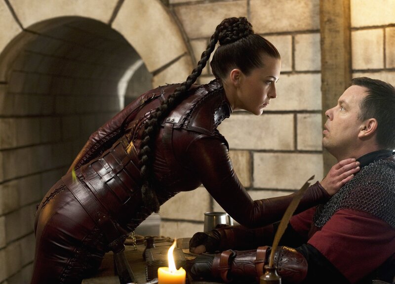 Woman in leather armor leans over man
