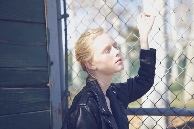 woman in leather jacket by fence