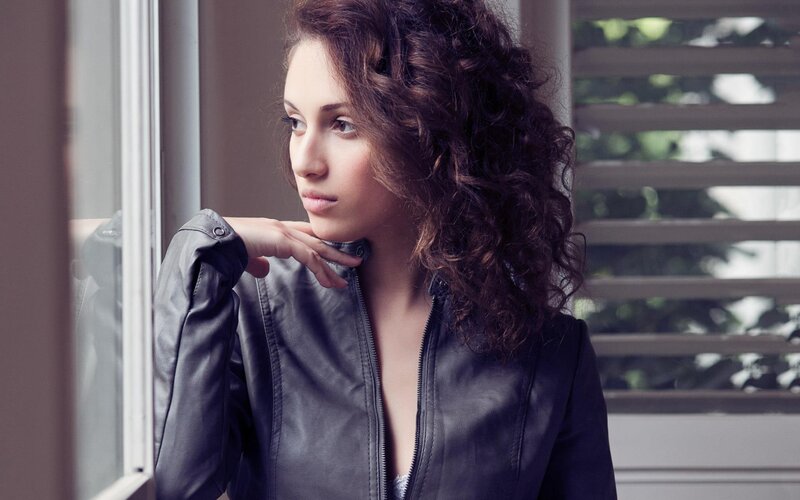 woman in leather jacket by window