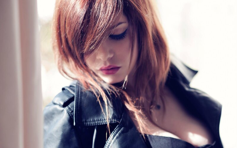 woman in leather jacket by window