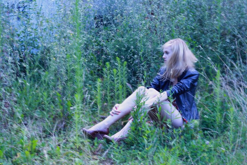 woman in leather jacket sitting in grass