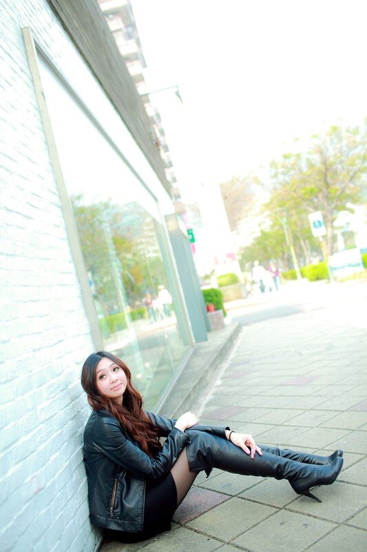 woman in leather jacket sitting on sidewalk