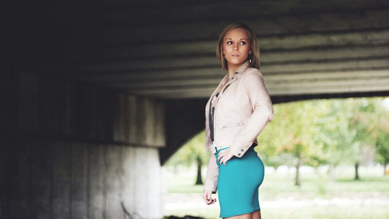 woman in leather jacket under bridge