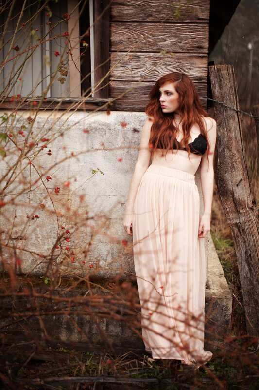 Woman in long skirt by wooden wall