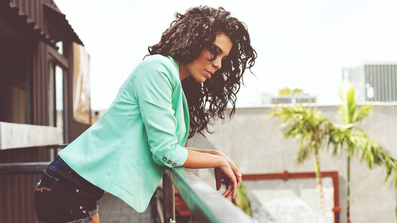 woman in mint blazer on balcony