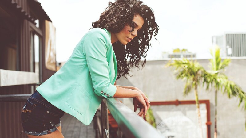 woman in mint blazer on balcony