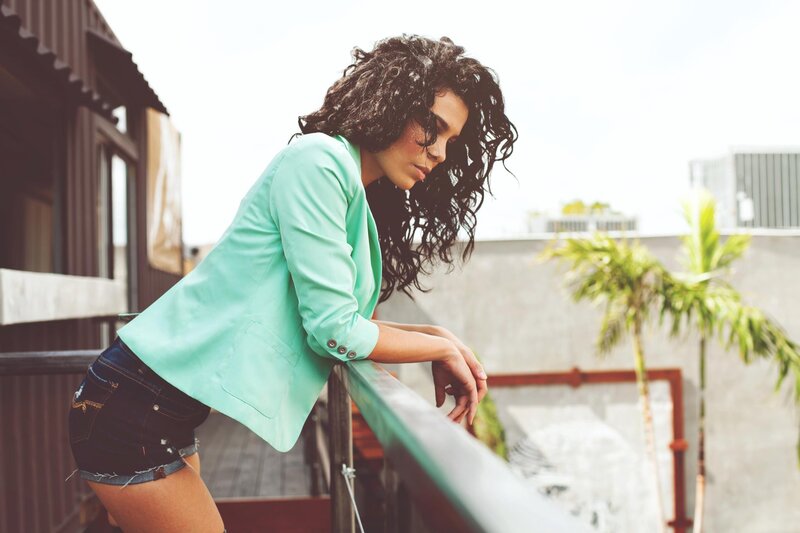 woman in mint blazer on balcony