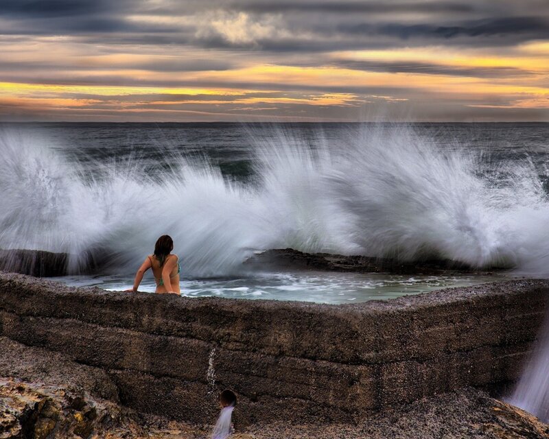 Woman in ocean pool at sunset