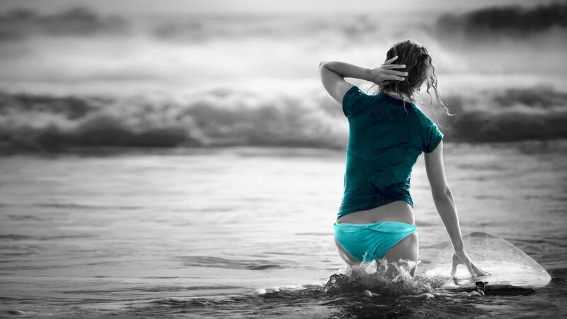 woman in ocean with surfboard