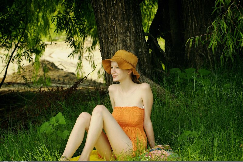 Woman in orange dress sitting in grass