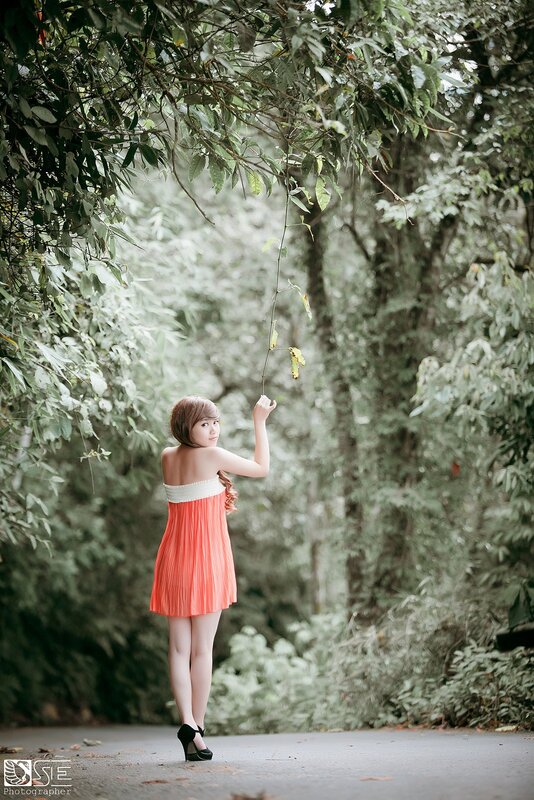 Woman in orange dress under trees