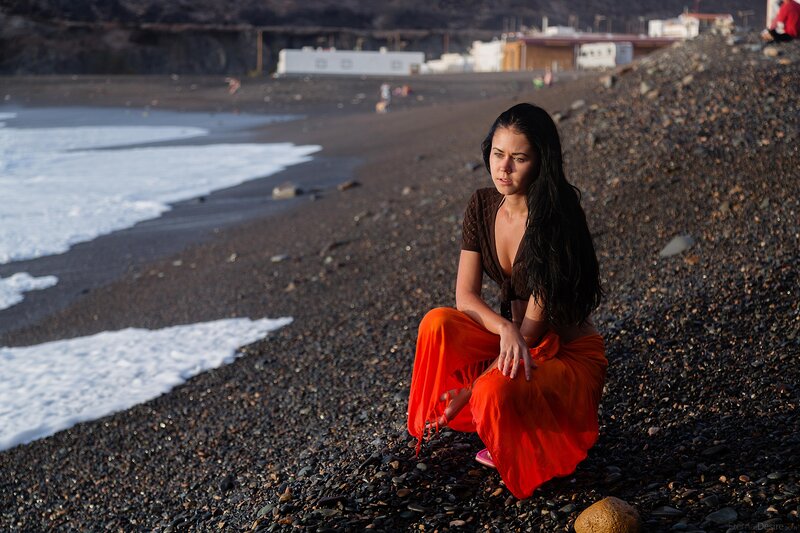 Woman in orange on pebble beach