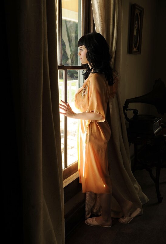 woman in orange robe by window
