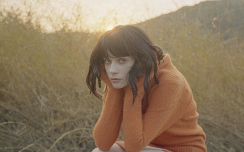 woman in orange sweater at sunset