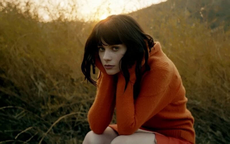 woman in orange sweater at sunset
