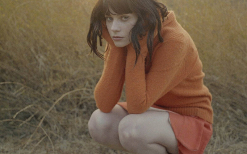 woman in orange sweater crouching