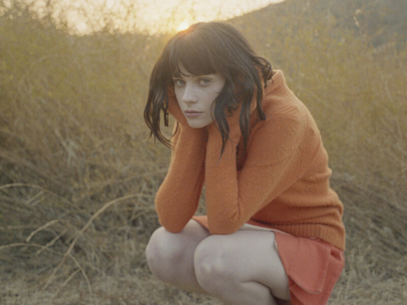 Woman in orange sweater crouching