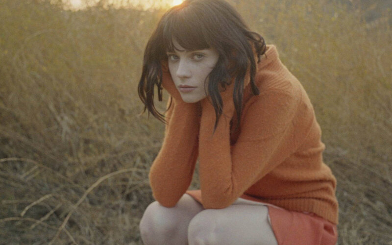 woman in orange sweater crouching