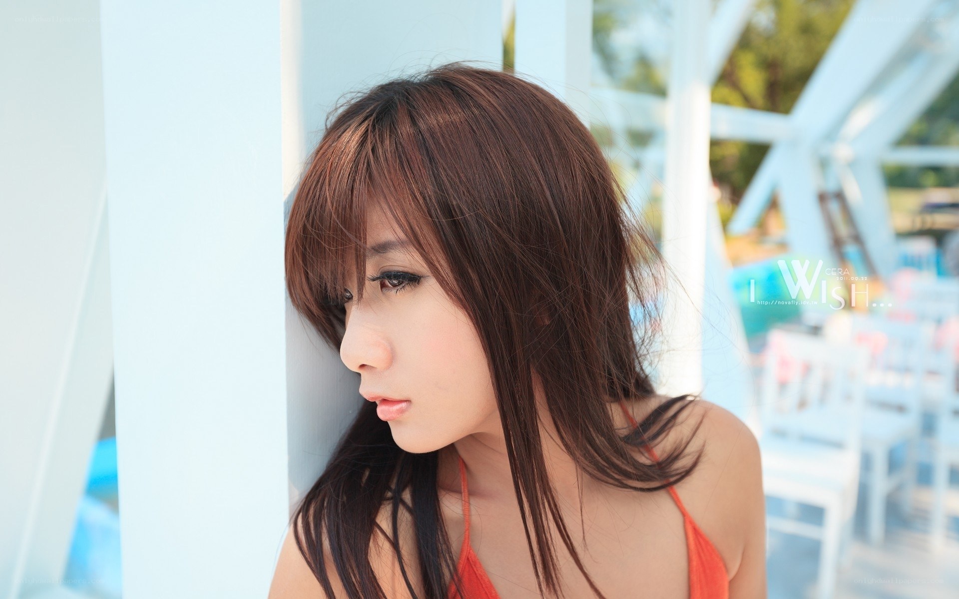 woman in orange top by white structure