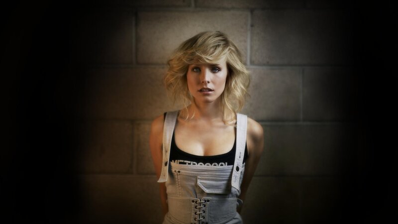 woman in overalls against brick wall