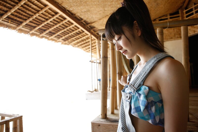 woman in overalls at bamboo hut