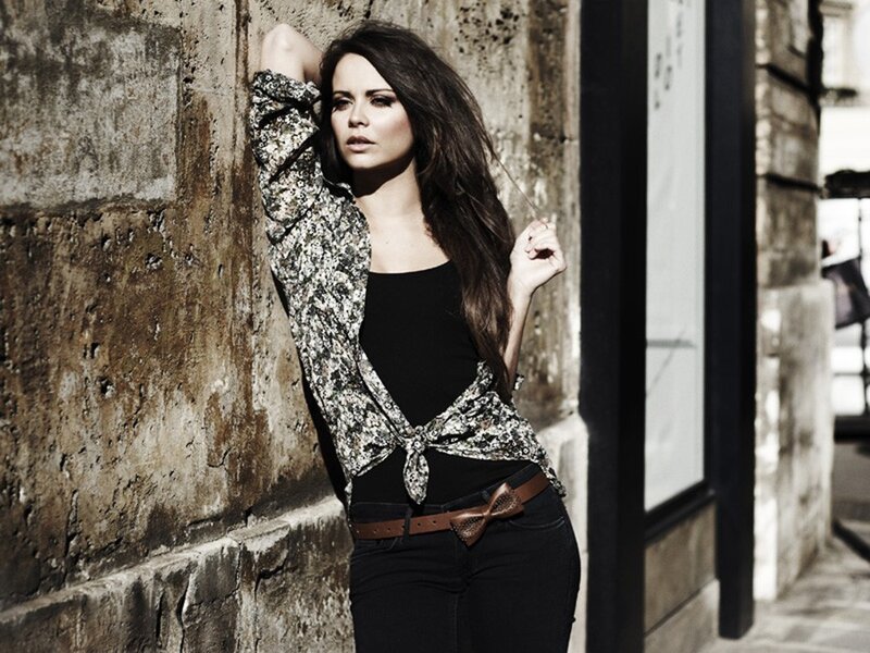 woman in patterned shirt leaning on wall