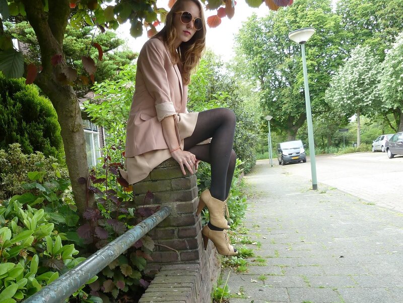 woman in pink blazer sitting on wall