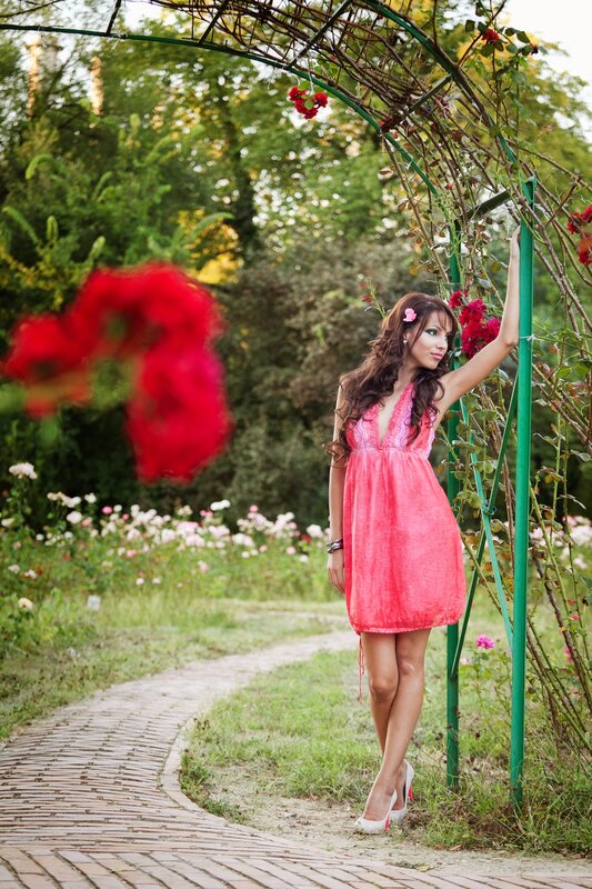 Woman in pink dress by rose arbor