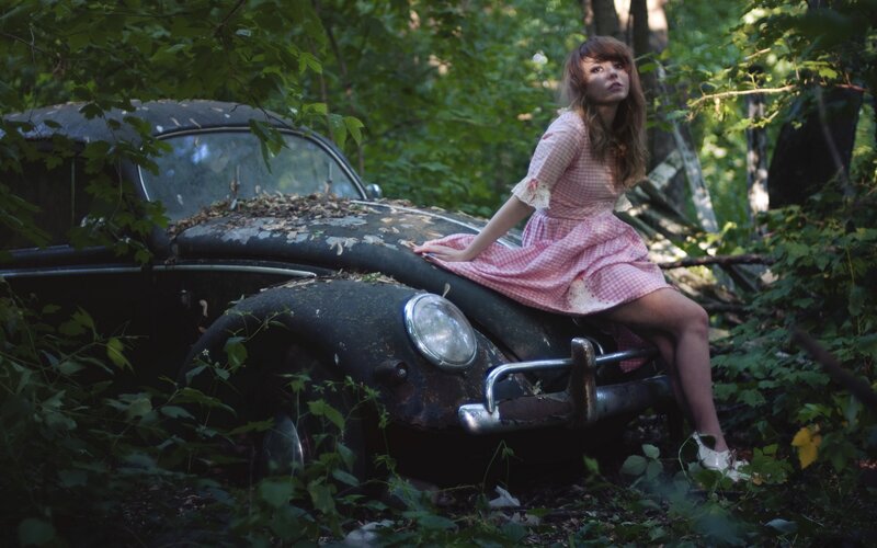 Woman in pink dress on old car