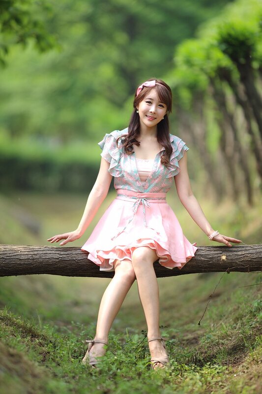 Woman in pink dress sitting on log