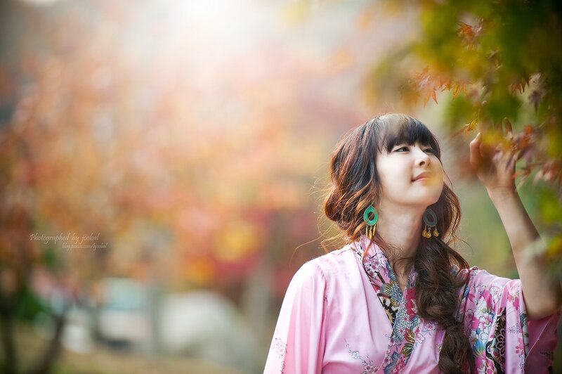 woman in pink kimono touching autumn leaves