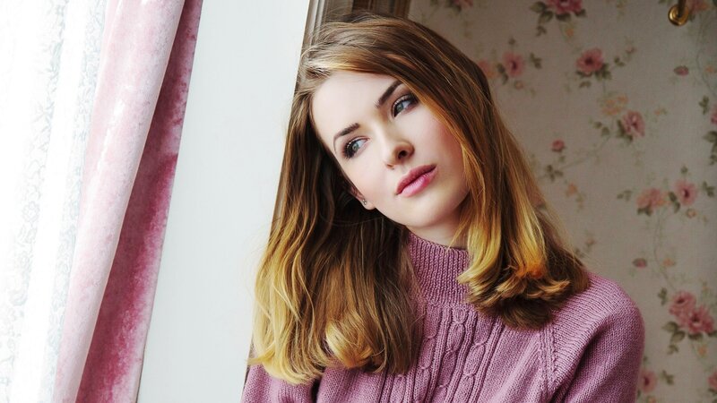 woman in pink sweater by window