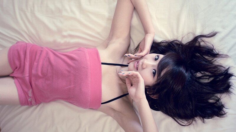 woman in pink top lying on bed