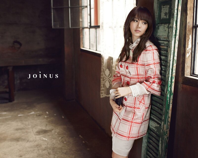 woman in plaid coat by window
