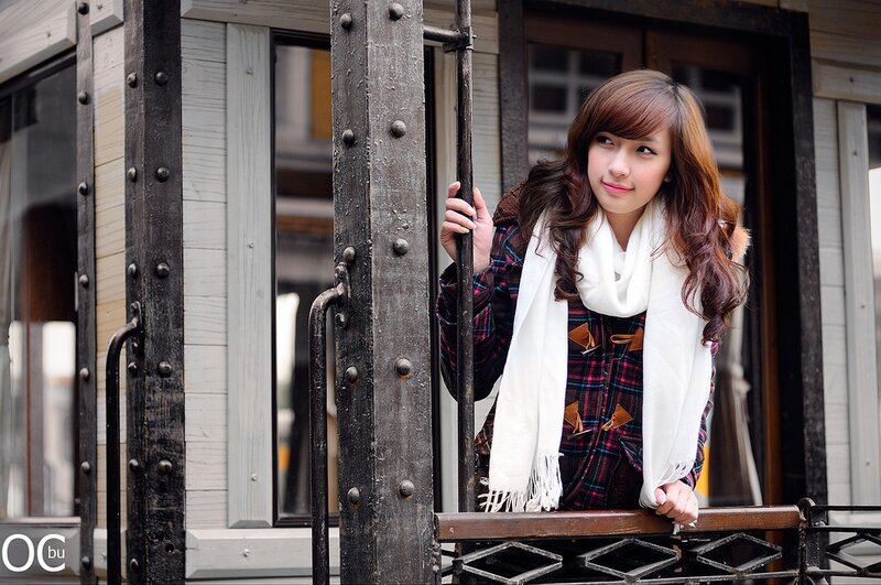 woman in plaid coat on balcony